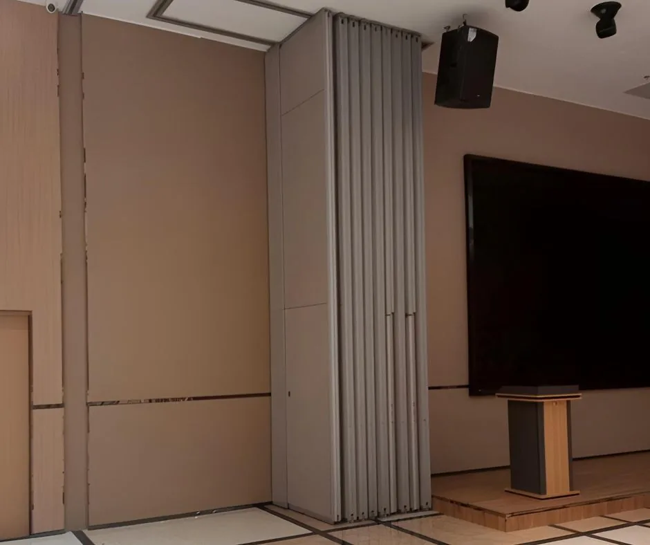 An operable partition wall folding open in a Philippine multipurpose hall, with the overhead track visible