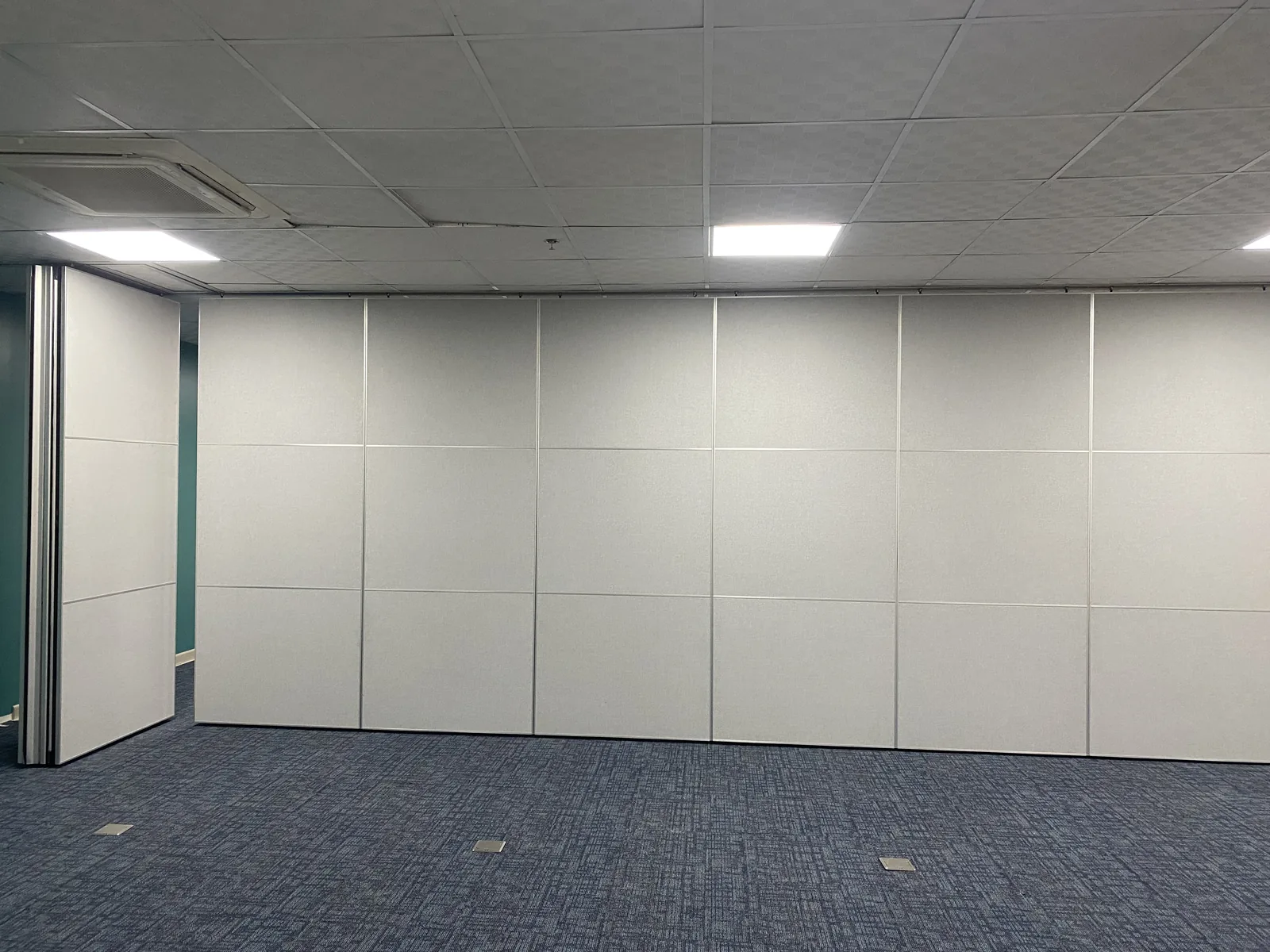 An operable partition wall closed across a Metro Manila office, with one end panel swung open to the space behind
