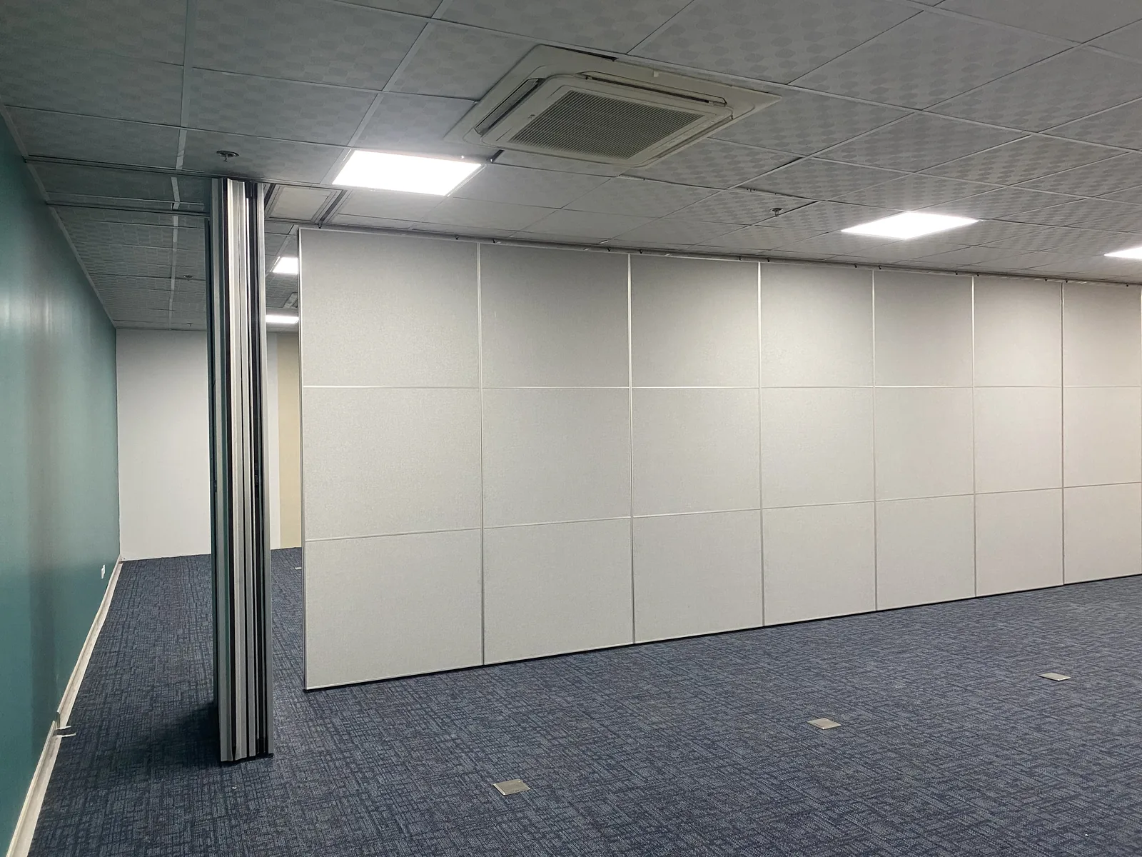 A long run of operable wall panels closing off one side of a Metro Manila office, with the aluminium jamb post in the foreground
