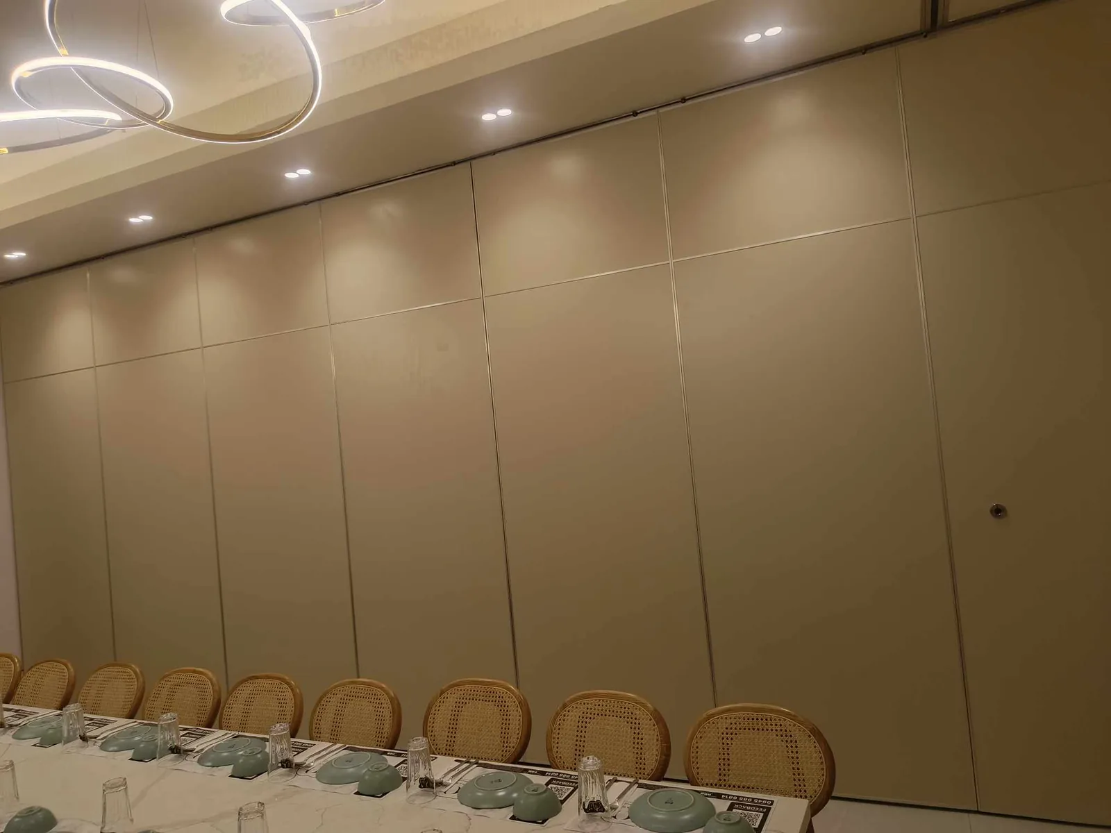 An operable partition wall closed behind a set banquet table in a Metro Manila function venue, with places laid for service