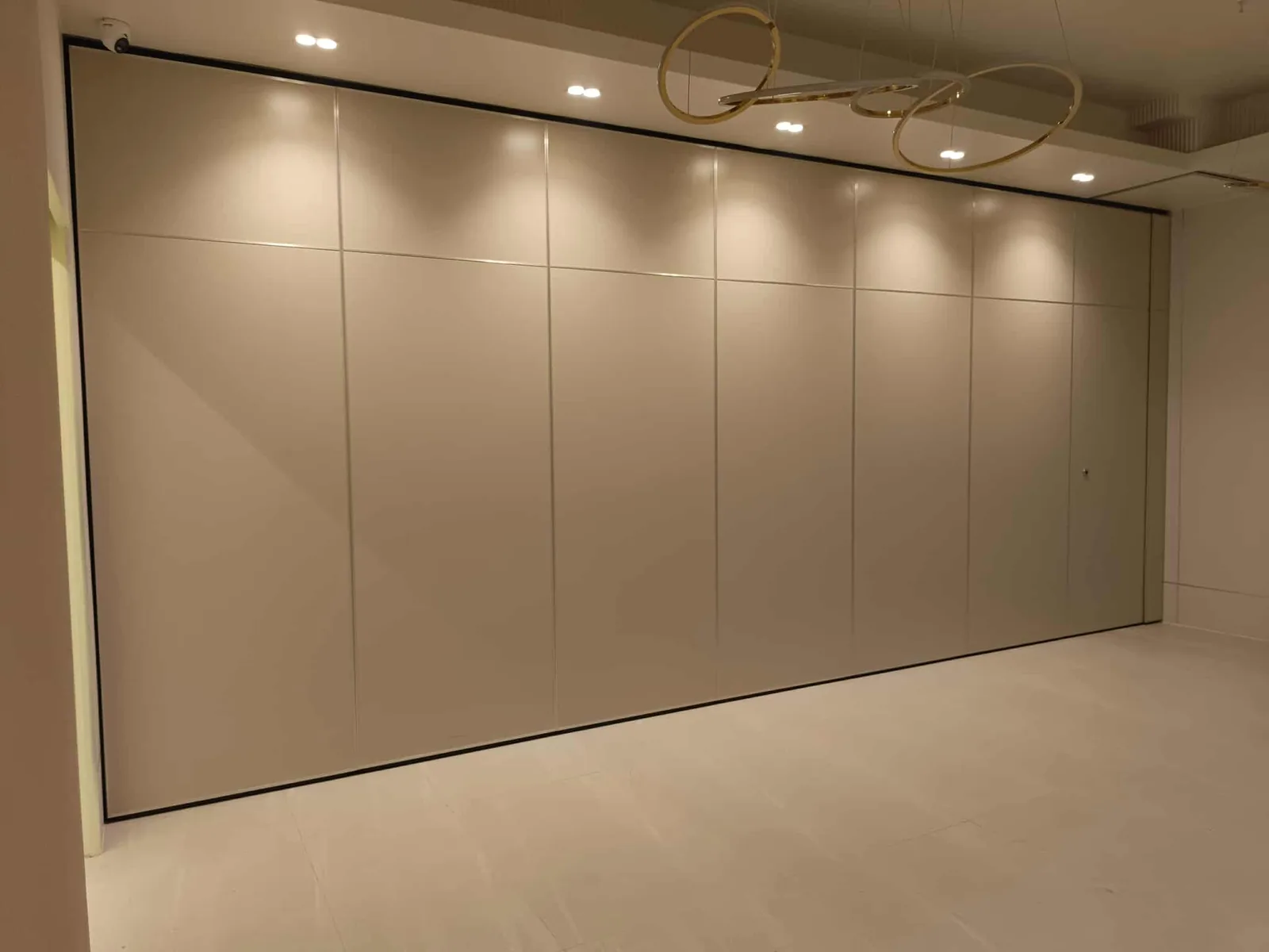 A cream-finished operable partition wall closed across a Metro Manila bar and function venue, lit by recessed downlights